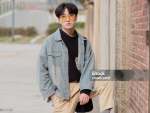 Portrait of a handsome Chinese young man standing and looking at camera with one leg on step, looking cool.